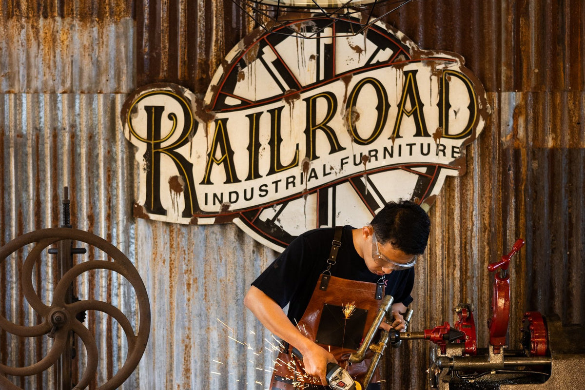 A Railroad maker grinding steel at the workbench under the Railroad sign